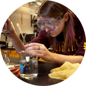 A U of M student concentrates on dropping a substance in a beaker