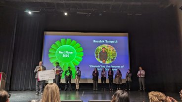 Koushik accepts his grand prize of $500 on stage at the University three minute thesis competition. 