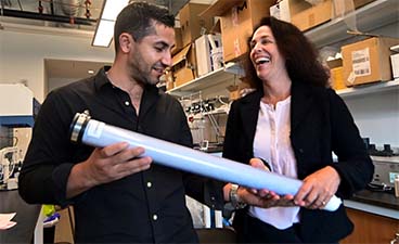 Abdennour Abbas and a team member holding a filter resembling a long white tube