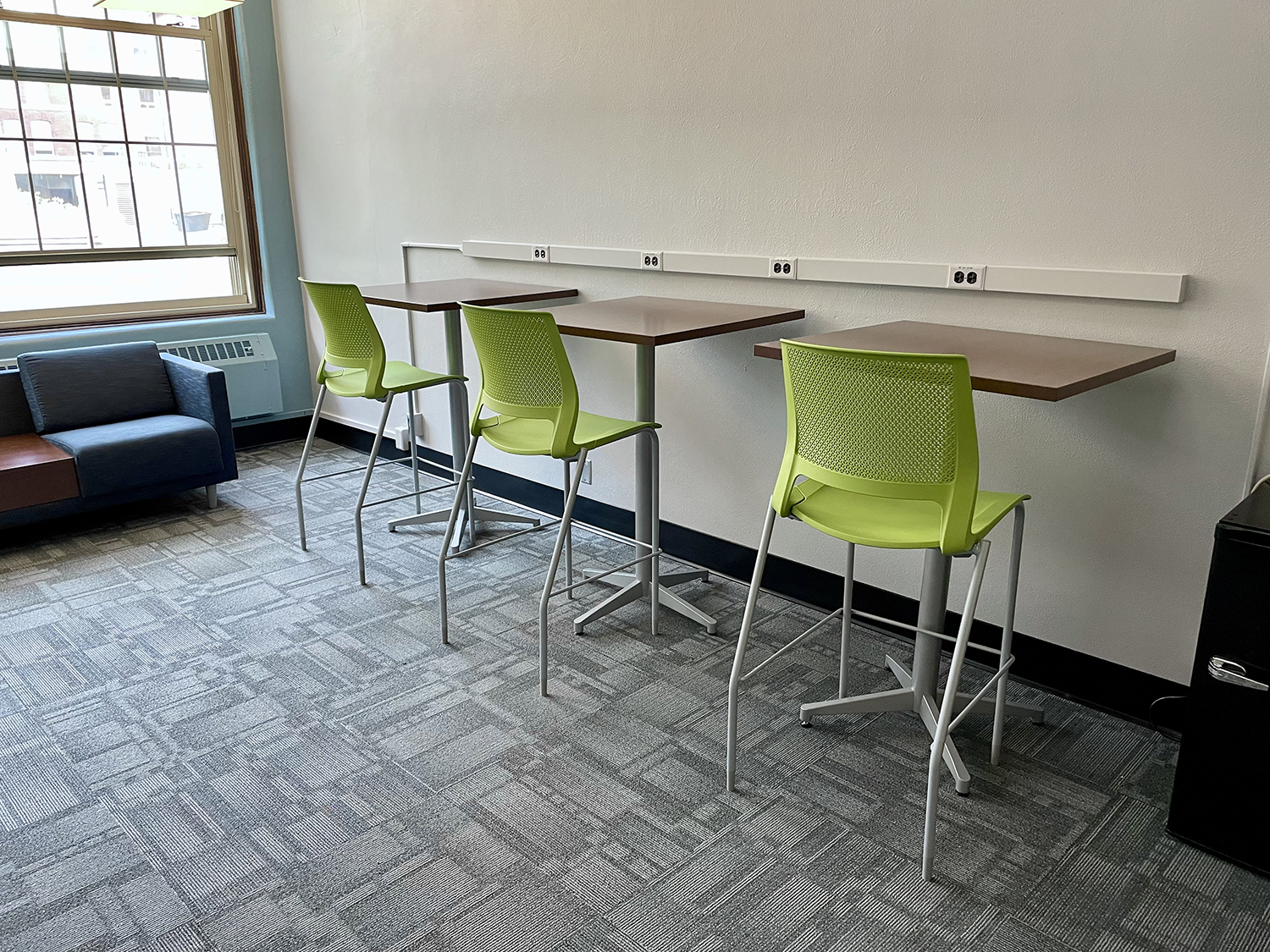 Updated furniture showing bright green chairs at individual student study tables, fresh paint and new lighting and carpet in the BAE building student loung.