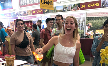 A visitor at the BBE table at the State Fair roasts marshmallow over a flame produced by biofuel