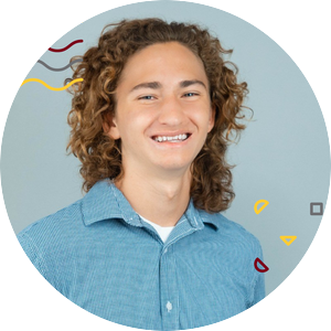 Patrick Olson has light brown curly hair and wears a blue button up shirt as he poses for a professional headshot