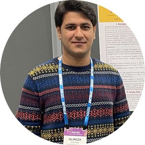 Alireza Sanaeifar wearing a colorful sweater and lanyard, posed in front of a information poster.