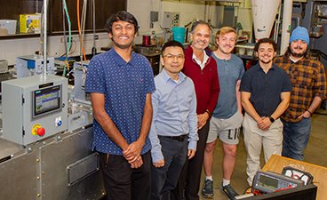 Professor Ramaswamy and his research team stand in front of their paper drying machine in Kaufert Lab.