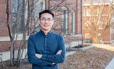 Dr. Zhenong Jin poses for a professional headshot in front of a brick building on the St. Paul campus