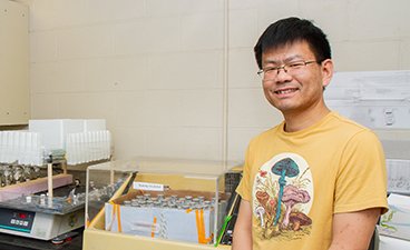 Jiwei stands in his lab in front of test tubes full of fungi samples.