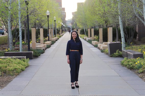 Vinni wears a navy blue belted jumpsuit as she poses on the walk of scholars located on the east bank campus in Minneapolis. 