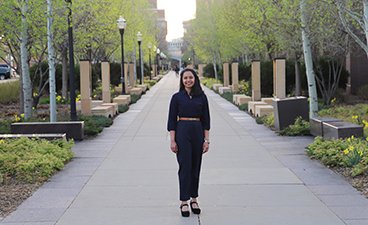 Vinni wears a navy blue belted jumpsuit as she poses on the walk of scholars located on the east bank campus in Minneapolis. 