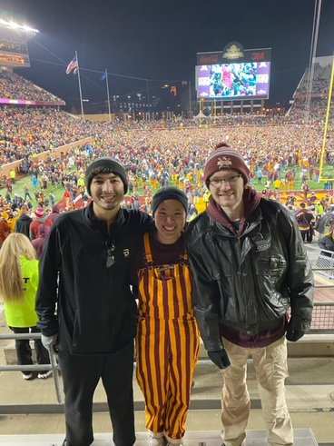 Madison wears maroon and gold coveralls as she poses with friends at a Gopher football home game. 