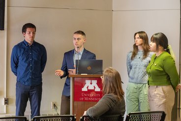 Four SSM students present their senior capstone in front of a small group of people.