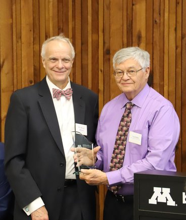 Leo Holm (right) accepts the distinguished alumni award from Bruce Wilson (left).